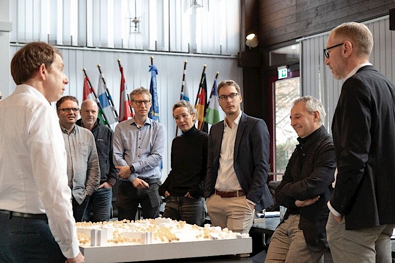 Gruppenbild im Sitzungssaal des Rathauses mit dem Modell der zukünftigen Stadtmitte im Mittelpunkt